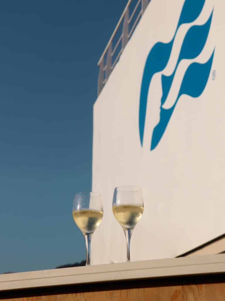 Glass of white wine enjoyed in the sun. Princess logo in the background.